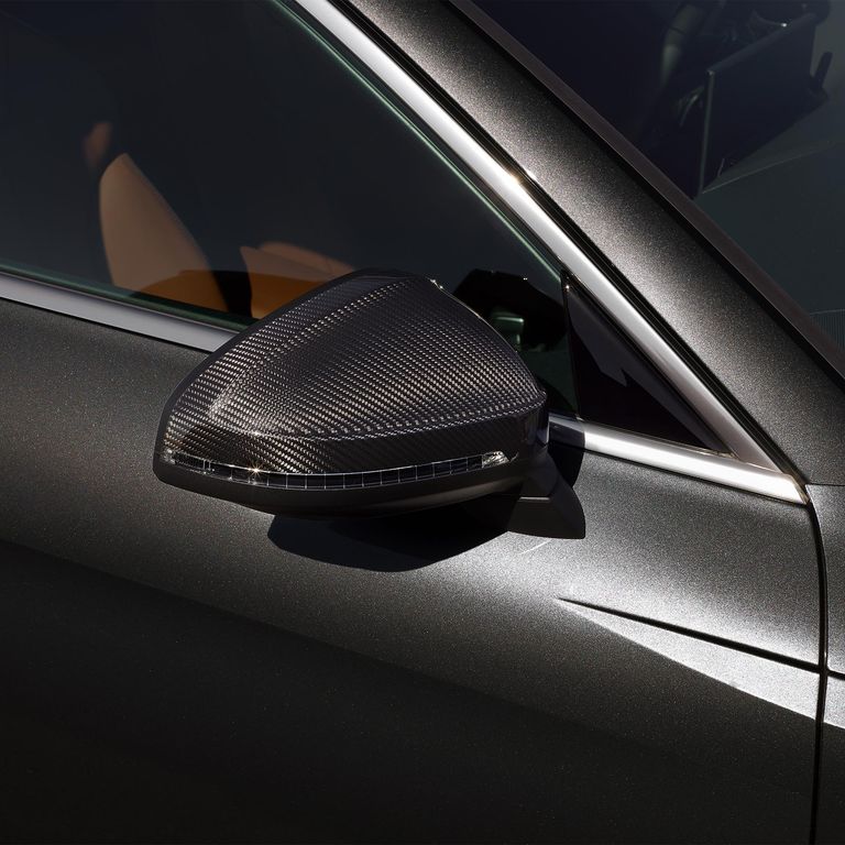A closeup of a carbon fibre door mirror on an Audi.